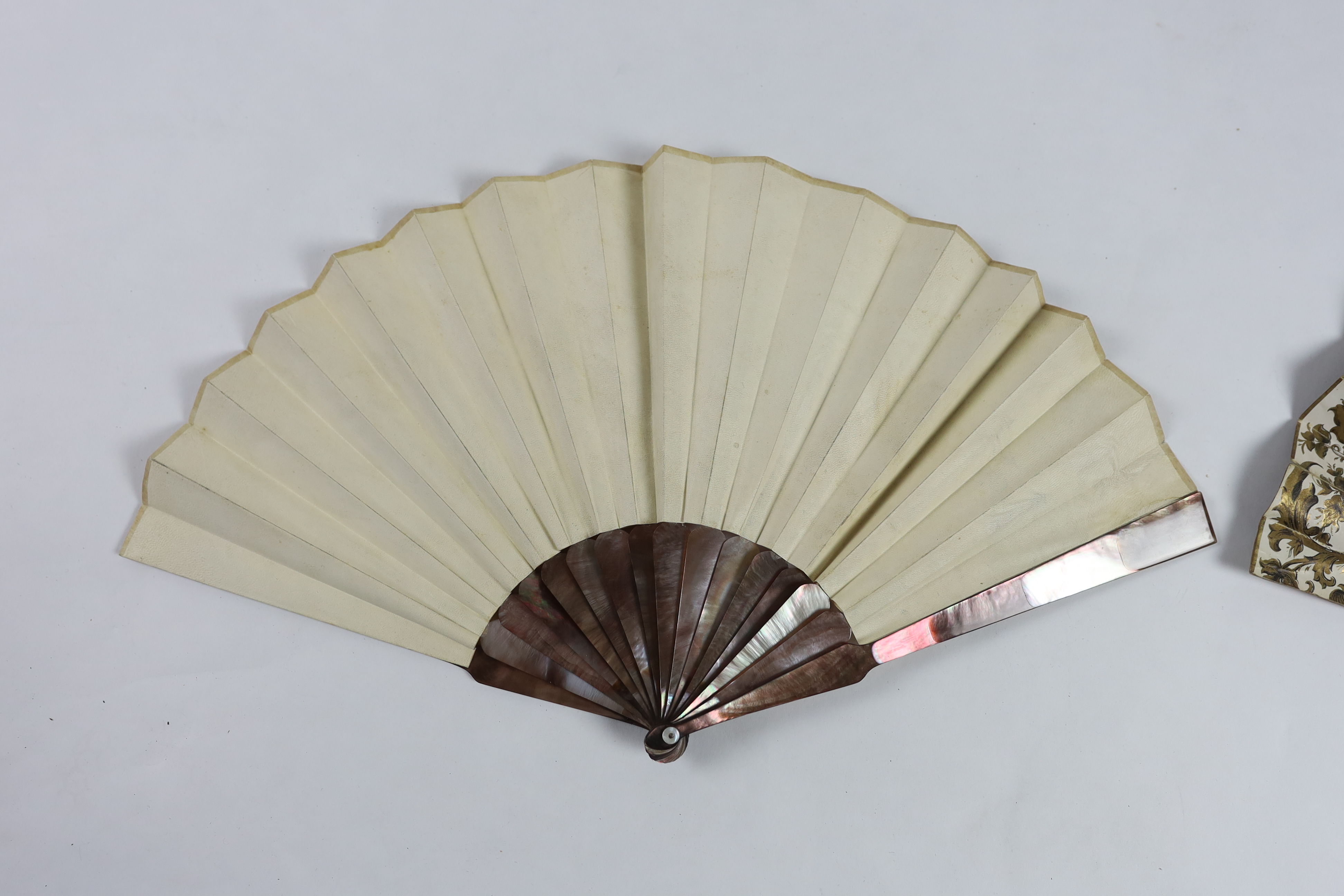 A 19th century mother of pearl and carved bone fan with ornate printed paper leaf, together with a similar Spanish fan of dancers, with mother of pearl guards, signed.